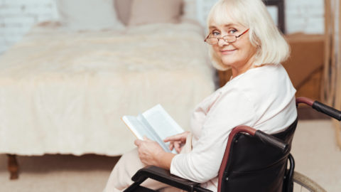 Pleasant disabled woman sittign in the wheelchair at home